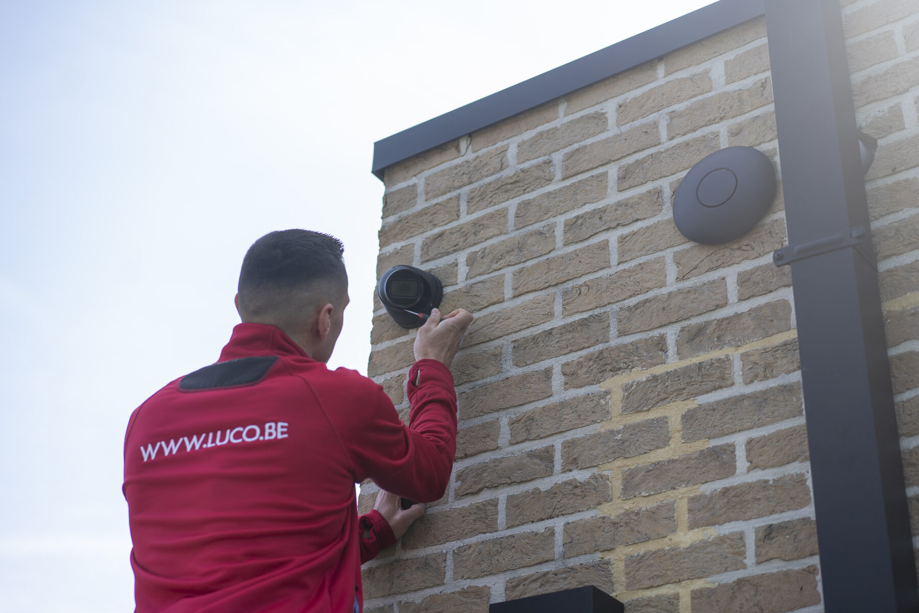 LUCO-technieker monteert een dome-camera aan een gevel