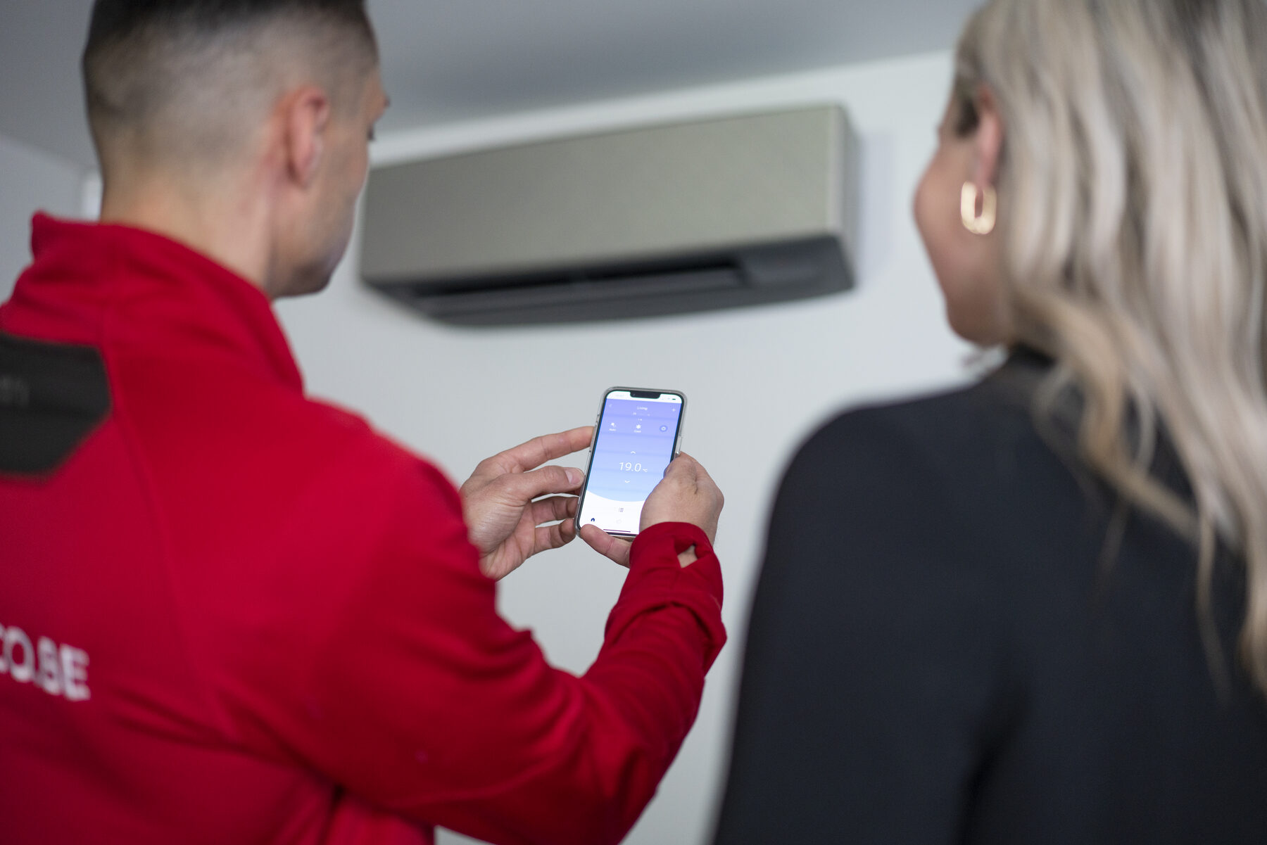LUCO-technieker toont de app aan een klant naast een airco-unit