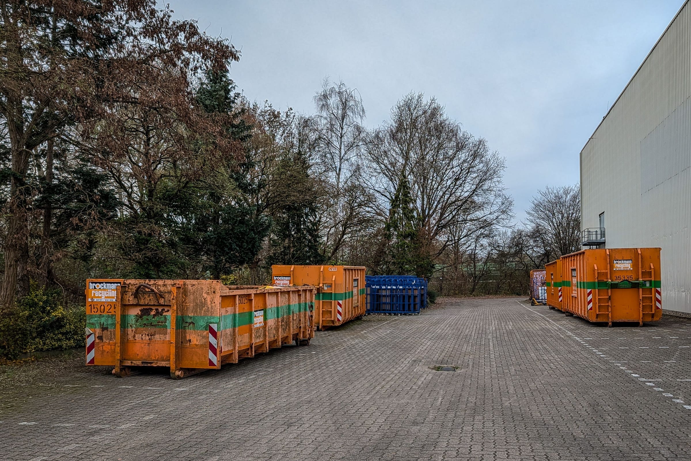 Afvalcontainers naast een bedrijfsloods